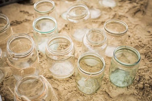 handmade chandeliers from a jars with a twine placed on a sand outdoors